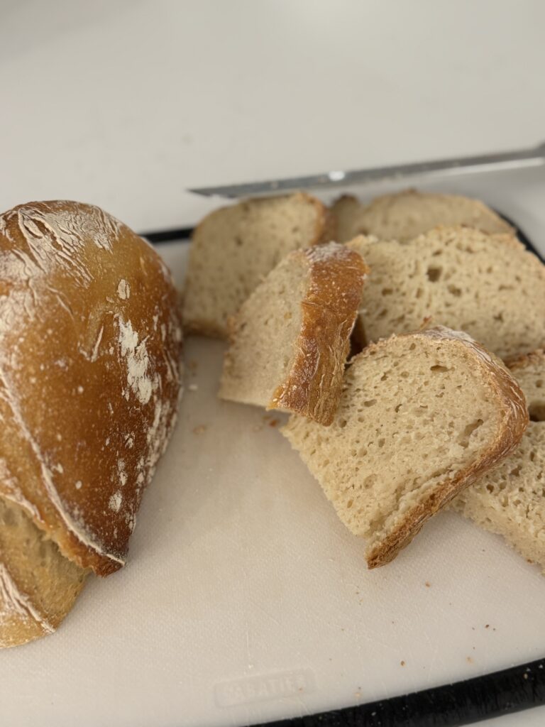 Sliced gluten free sourdough bread showing open crumb texture with crispy crust on a cutting board